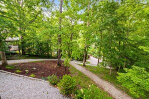 A forested area with a gravel path, a wooden deck, and a small garden bed. - Lakefront - Norris Lake - Hot Tub, 2 Slip Covered Dock, Kayaks, ATV trails (Jacksboro)
