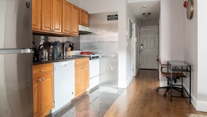 Une cuisine moderne dotée de meubles en bois, d’appareils électroménagers en acier inoxydable et d’un plan de travail sur lequel sont disposés divers ustensiles de cuisine.