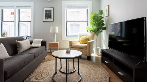 A modern living room with a sofa, a coffee table, a TV, and a chair.