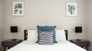 A hotel room with a large bed, two bedside tables with lamps, and two framed pictures on the wall. - Airy 1BR Walkable to Everywhere in Boston | W+D (Boston)