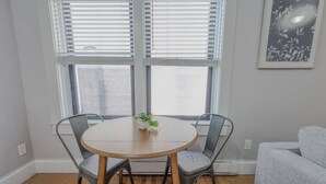 A dining area with a round table, two chairs, and a potted plant.