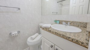 A bathroom with a white toilet, a sink with a granite countertop, and a mirror above the sink.