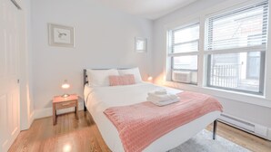 Une chambre à coucher avec un lit, une table de chevet, une lampe et une fenêtre avec des stores.