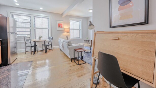Un appartement moderne comprenant un coin repas, un canapé, un bureau et une grande armoire en bois.