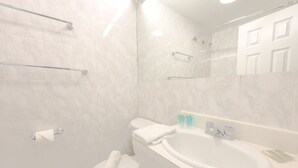 Une salle de bain avec un lavabo blanc, un miroir et des toilettes.