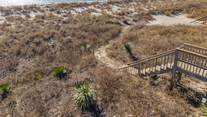 Una playa con una escalera de madera que baja hacia la arena.