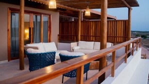 A covered outdoor seating area with two white sofas and blue woven chairs, wooden railings, and hanging pendant lights. - House in Prea  (Caiçara)