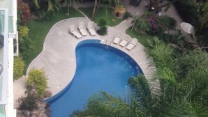 Vista aerea di una piscina circondata da lettini e vegetazione tropicale.
