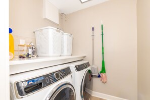 A laundry area with a washing machine, a dryer, and a mop on a wall. - Do Knot Disturb Oceanfront Private Pool Renovated Sleeps 14 (Emerald Isle)