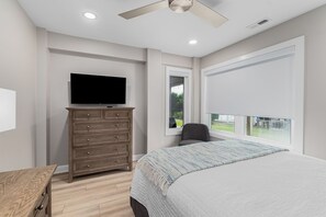A bedroom with a bed, a dresser, a television, and a window with a view of the outdoors. - Do Knot Disturb Oceanfront Private Pool Renovated Sleeps 14 (Emerald Isle)