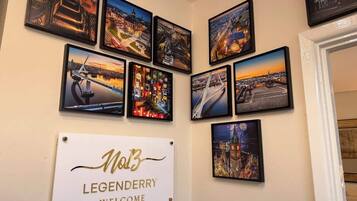 Eine Wand mit mehreren gerahmten Fotos von Stadtansichten und einem Willkommensschild für Legenderry.