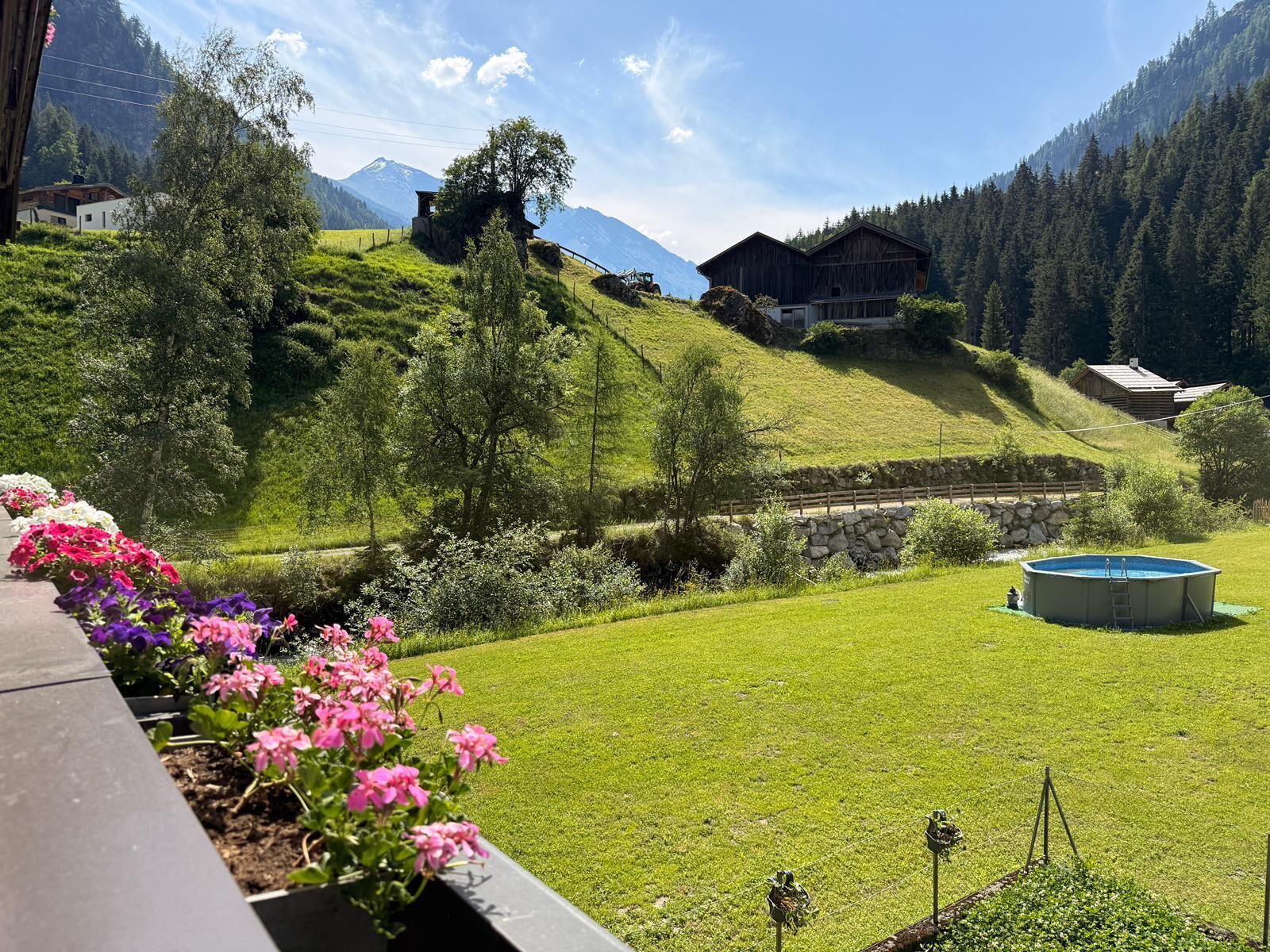 Un paysage montagneux avec un chalet en bois, une piscine et un parterre de fleurs.