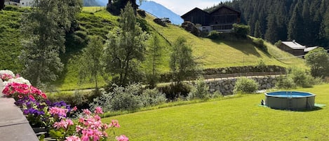 Un paysage montagneux avec un chalet en bois, une piscine et un parterre de fleurs.
