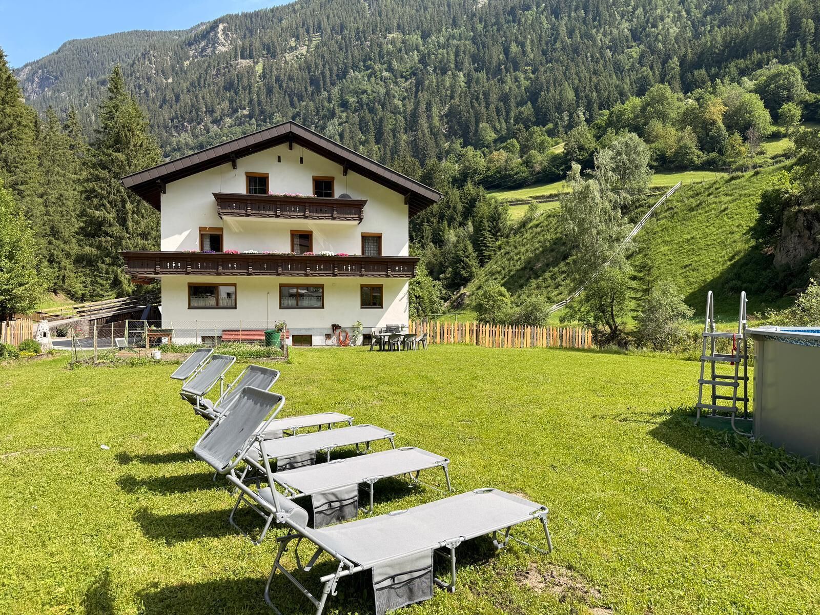 A two-story building with a balcony, surrounded by a grassy area with sun loungers.