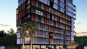 Un edificio de varios pisos con diseño moderno, que destaca un cartel con el nombre "EMU NAH!" en la fachada.