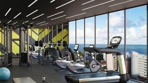 Un gimnasio moderno con equipo cardiovascular, máquinas de pesas y un amplio ventanal con vistas a la ciudad.