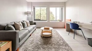 Una sala de estar moderna con un sofá gris, una mesa redonda para café y un sillón azul.