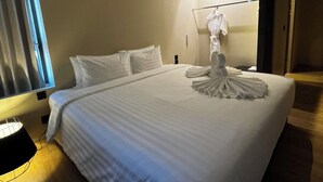 Habitación de hotel con una cama grande, una lámpara de noche, una ventana con cortinas y una bata colgada en un perchero.
