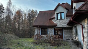 A stone house with a tiled roof, a stone chimney, and a small garden with plants and a pathway.