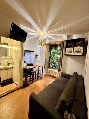 A compact living space with a kitchenette, a dining area, and a seating area with a sofa. - **2 min from the Jet d'Eau | Renovated 24 m² studio, downtown Geneva** (Genève)