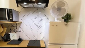 Eine kompakte Küche mit Mikrowelle, Toaster und einem kleinen Ventilator.