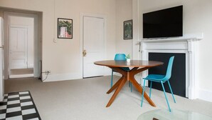 Un coin repas avec une table ronde et deux chaises, une cheminée et un téléviseur fixé au-dessus.