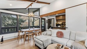 Een moderne woonkamer met een groot raam, een eethoek en een keuken.
