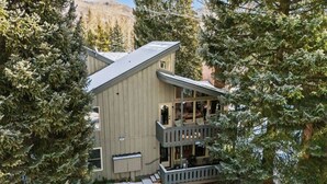 Een gebouw met twee verdiepingen en een balkon, omgeven door altijdgroene bomen.