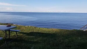 En gräsyta med ett picknickbord och utsikt över havet.