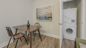A room with a wooden dining table, two chairs, a vase, a painting, and a laundry machine. - Bold, Spacious 2br in Boston`s Financial District (Boston)