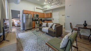 A modern kitchen with stainless steel appliances, a dining area with a table and chairs, and a living room with a sofa and a glass coffee table. - Bold, Spacious 2br in Boston`s Financial District (Boston)