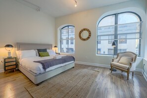 A bedroom with a bed, bedside tables, a chair, and large windows. - Bold, Spacious 2br in Boston`s Financial District (Boston)