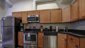 A kitchen with stainless steel appliances, wooden cabinets, a dishwasher, and a coffee maker. - Bold, Spacious 2br in Boston`s Financial District (Boston)