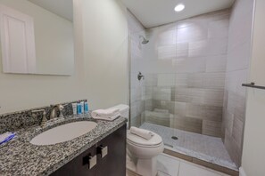 A bathroom with a granite countertop sink, a toilet, and a glass-enclosed shower. - Milk153-3B-2/2 · Cozy 2br in Boston FIDI District (Boston)