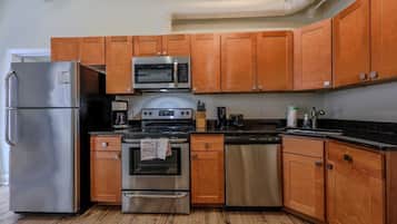 A kitchen with wooden cabinets, stainless steel appliances, and a black countertop.