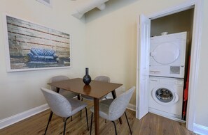 A dining area with a table and chairs, a vase, a painting, and a laundry machine. - Milk153-3B-2/2 · Cozy 2br in Boston FIDI District (Boston)