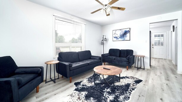 En moderne stue med en mørkeblå sofa, et rundt sofabord og en loftsvifte.