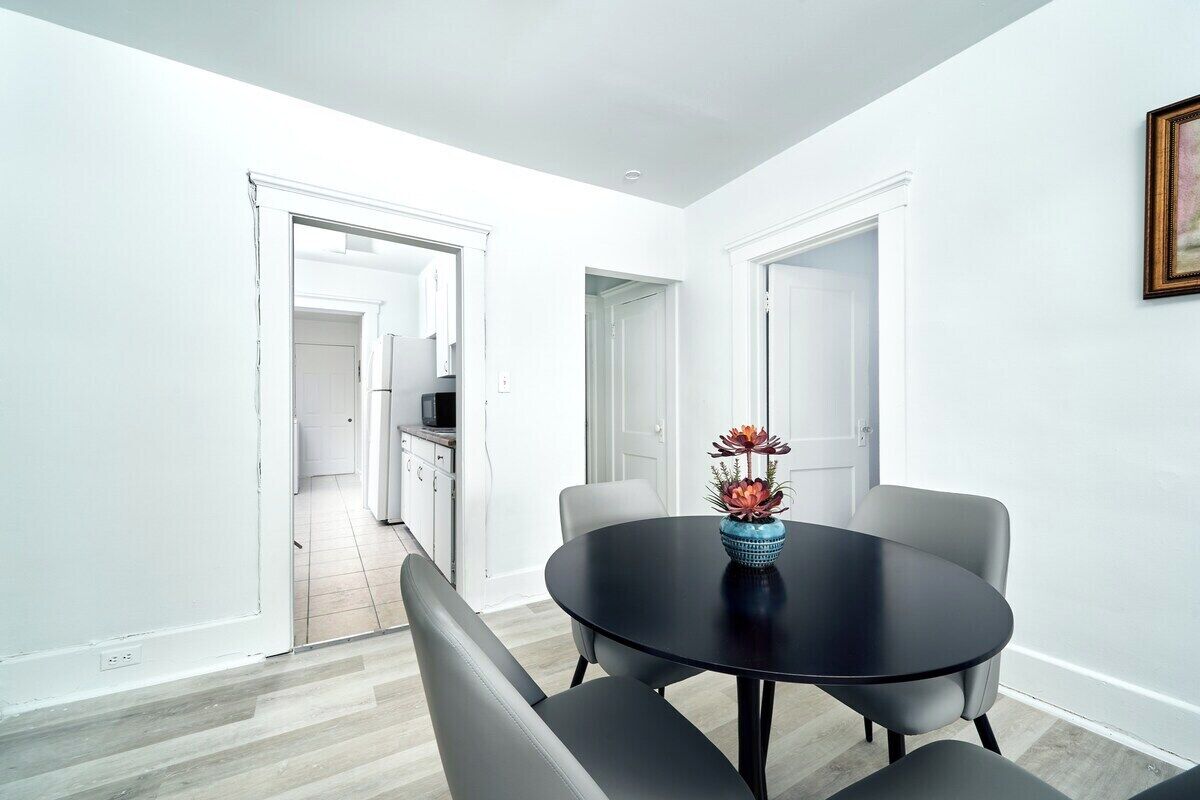 A dining area with a round table, two chairs, and a vase with flowers.