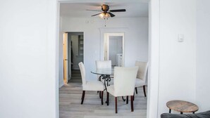 A dining area with a glass table and four chairs, a ceiling fan, and a small round table. - 1036 Assumption · Bright 3 BDRM Unit Perfect for Longer Stays (Windsor)