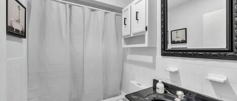 A bathroom with a bathtub, toilet, sink, and a large mirror.
