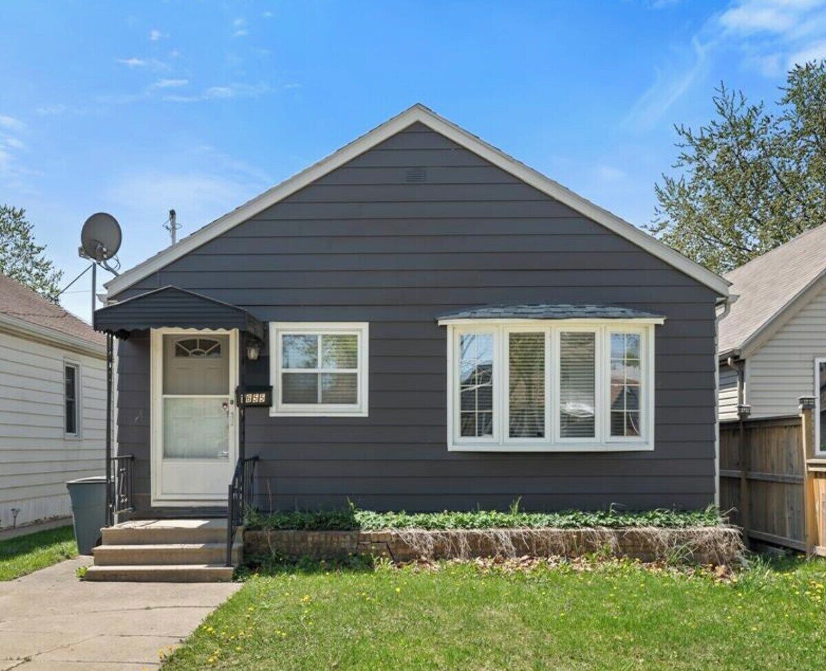 A two-story house with a dark gray exterior, white trim, and a front porch.