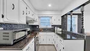 Uma cozinha moderna com armários brancos, bancada preta e parede de tijolos decorativa.
