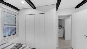 Quarto com cama, guarda-roupa e janela com persianas.