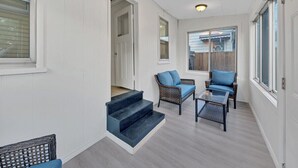 Uma sala de sol com escada que leva a um andar superior, móveis de vime e grandes janelas.