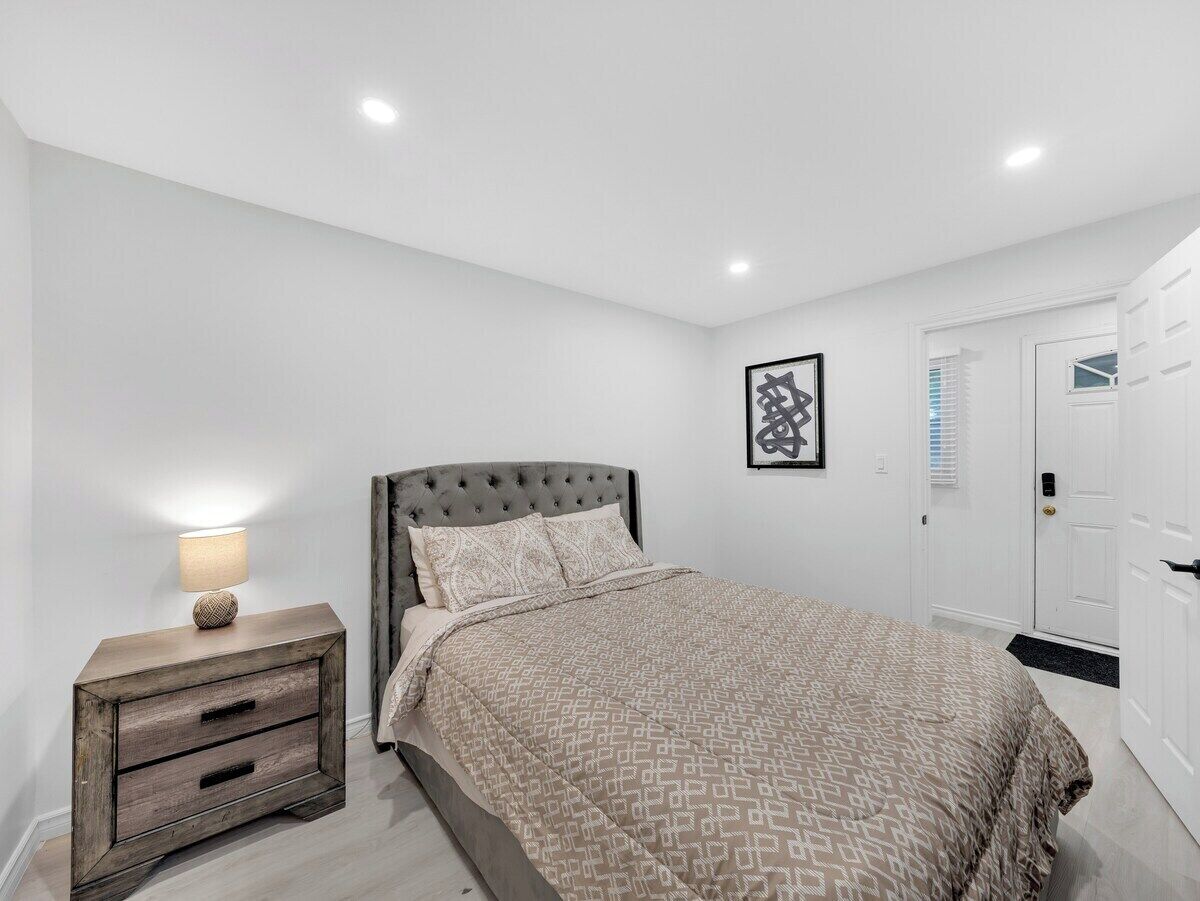 Une chambre à coucher avec un lit, une table de chevet avec une lampe, une armoire et un tableau encadré au mur.