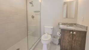 A modern bathroom with a glass-enclosed shower, a white toilet, a granite countertop sink, and a wooden vanity. - Milk153-3D-2/2 · 2br/2ba FIDI Apt | Keyless Entry | Walk anywhere! (Boston)