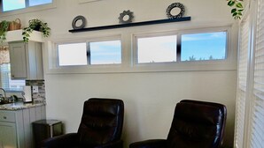 Quarto com duas poltronas de couro, cozinha e uma grande janela com vista.