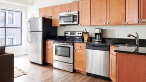 Una cucina moderna con elettrodomestici in acciaio inox, mobili in legno e un piano di lavoro nero.