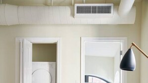 Un soggiorno moderno con un tavolino in vetro, una poltrona verde, una lavatrice e un termosifone.