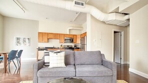 Una sala de estar moderna con un sofá gris, una mesa de centro y una zona de comedor con sillas.